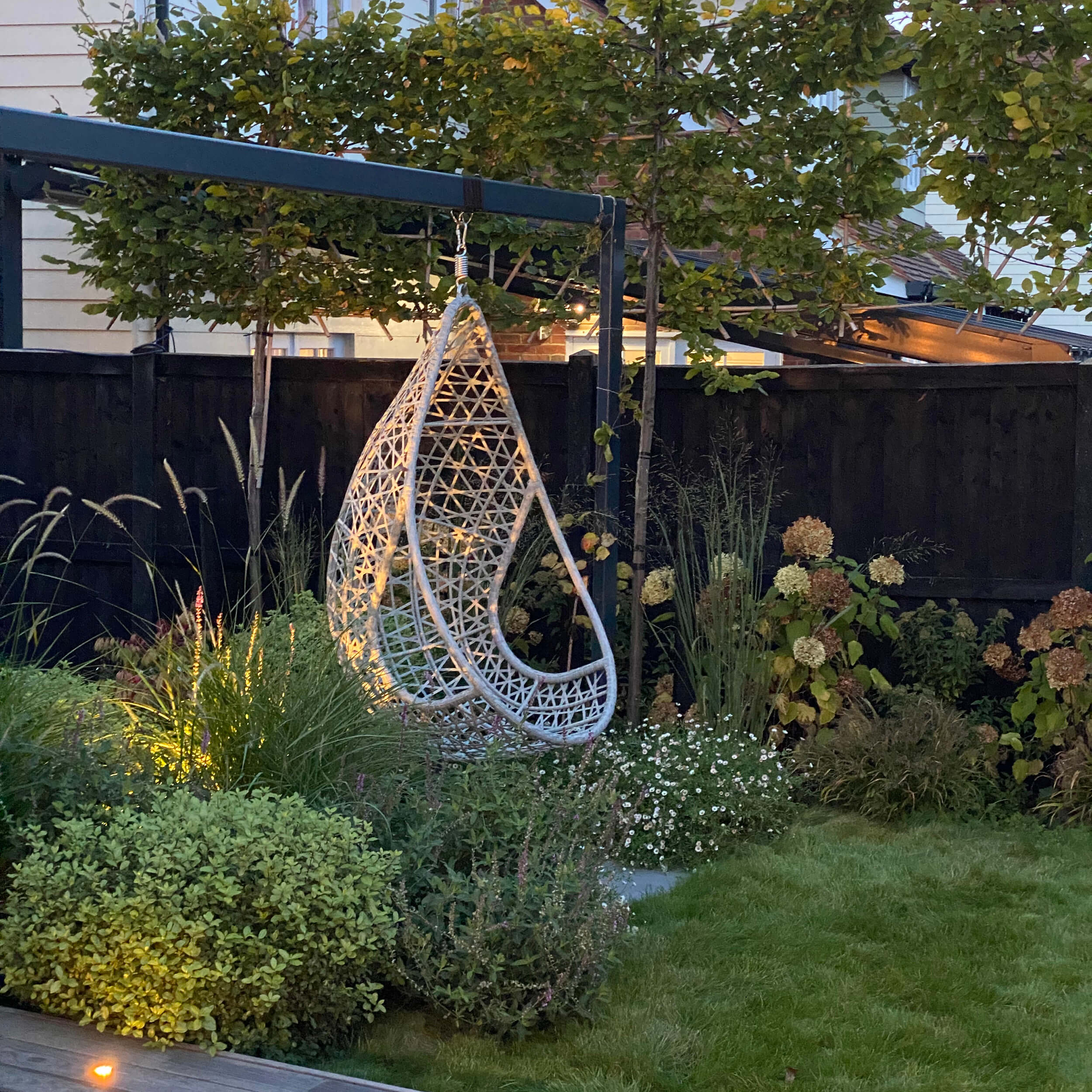 A swing seat hangs from the bespoke pergola above the herbaceous border