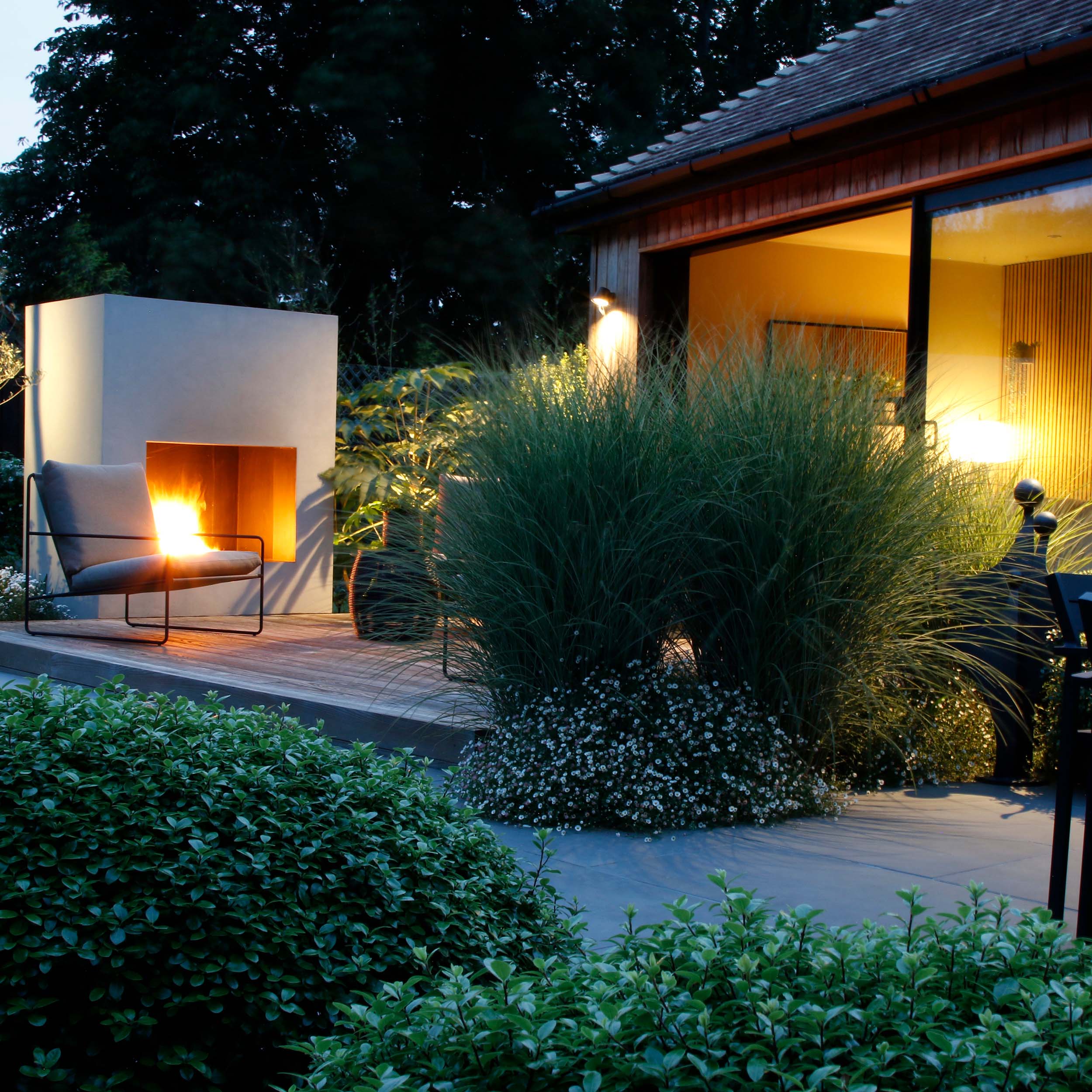 Our modern garden design in Longfield photographed at night with the outdoor fireplace in action
