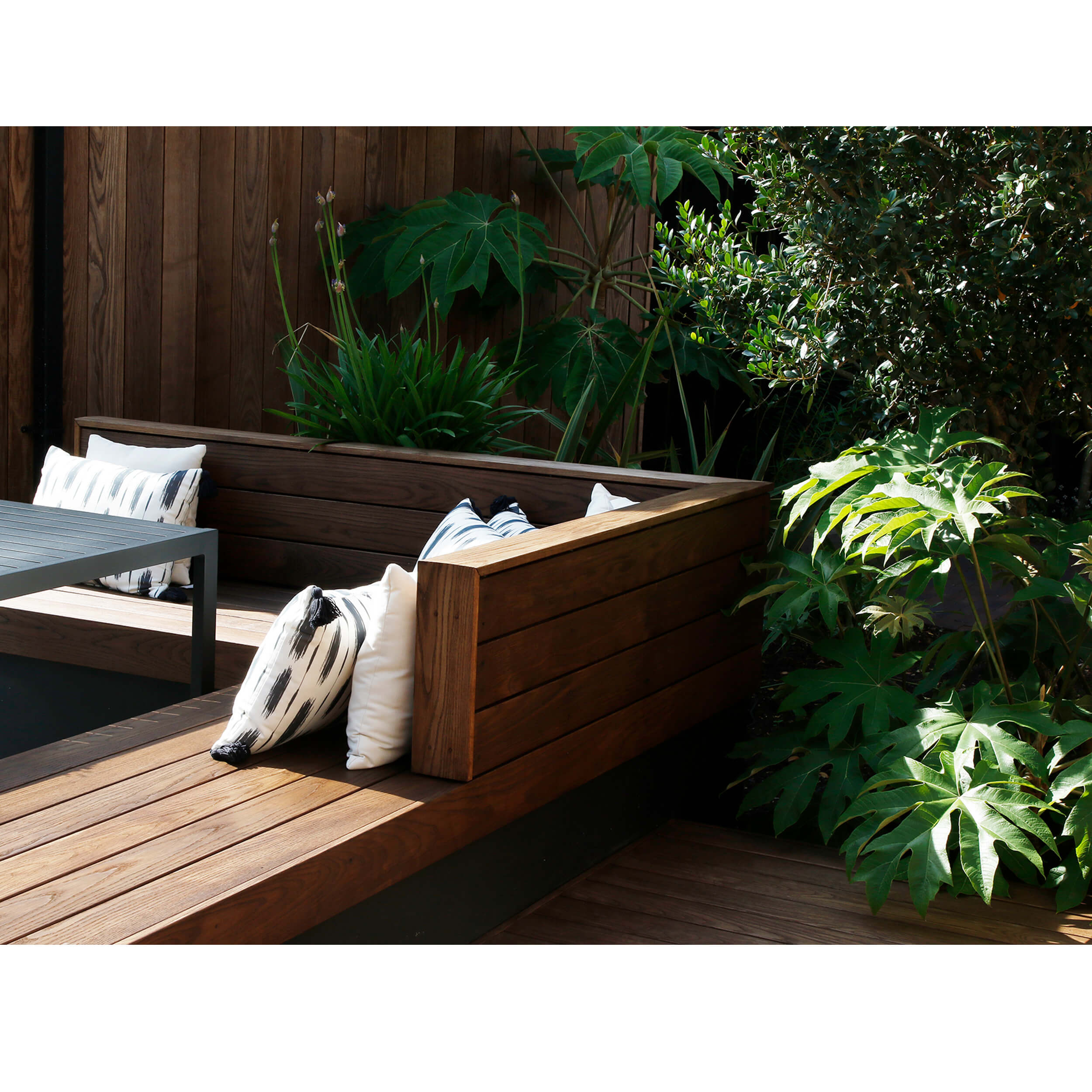 A bespoke wooden corner bench seat made with design boards and softened with cushions