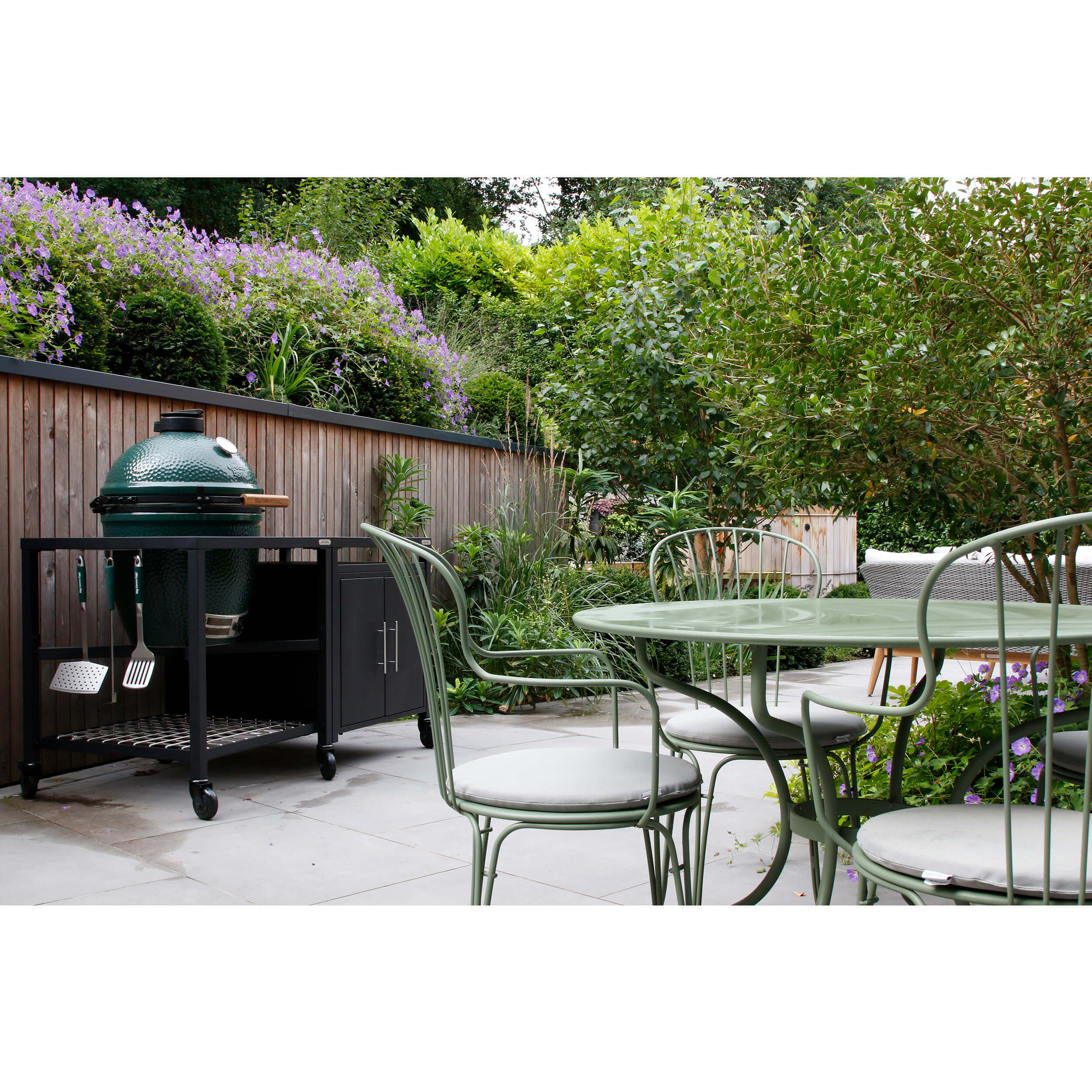A big green egg barbecue beside a green Fermob table and chairs