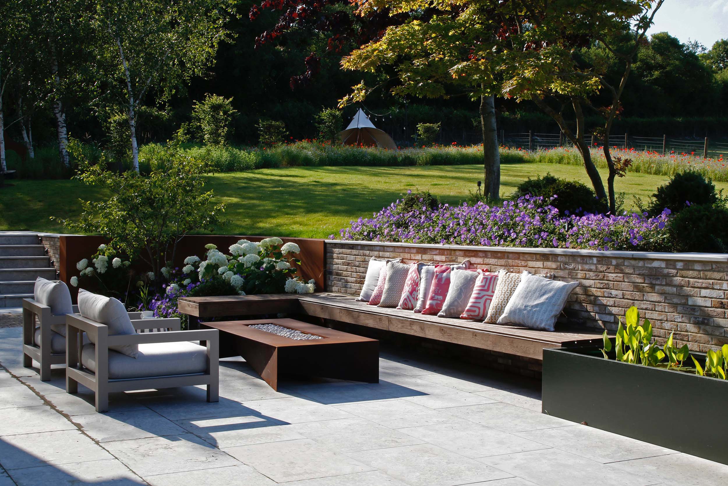 A large bespoke L-shaped bench around a fire pit ensure entertaining can continue well into the evening. A real social space.